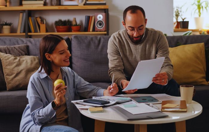 Couple sitting on a living room couch, discussing how to buy a house when mortgage rates are high